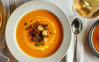 a beautifully decorated thanksgiving table, with a stunning pumpkin soup, a buttery tart, savory gravy, and a delicious fondant cake.